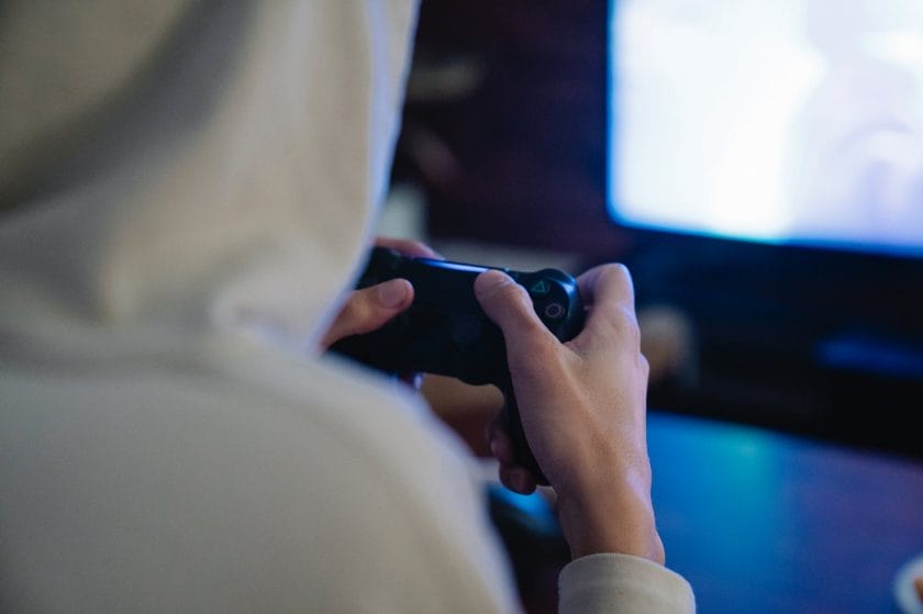 crop gamer with joystick playing video game against monitor