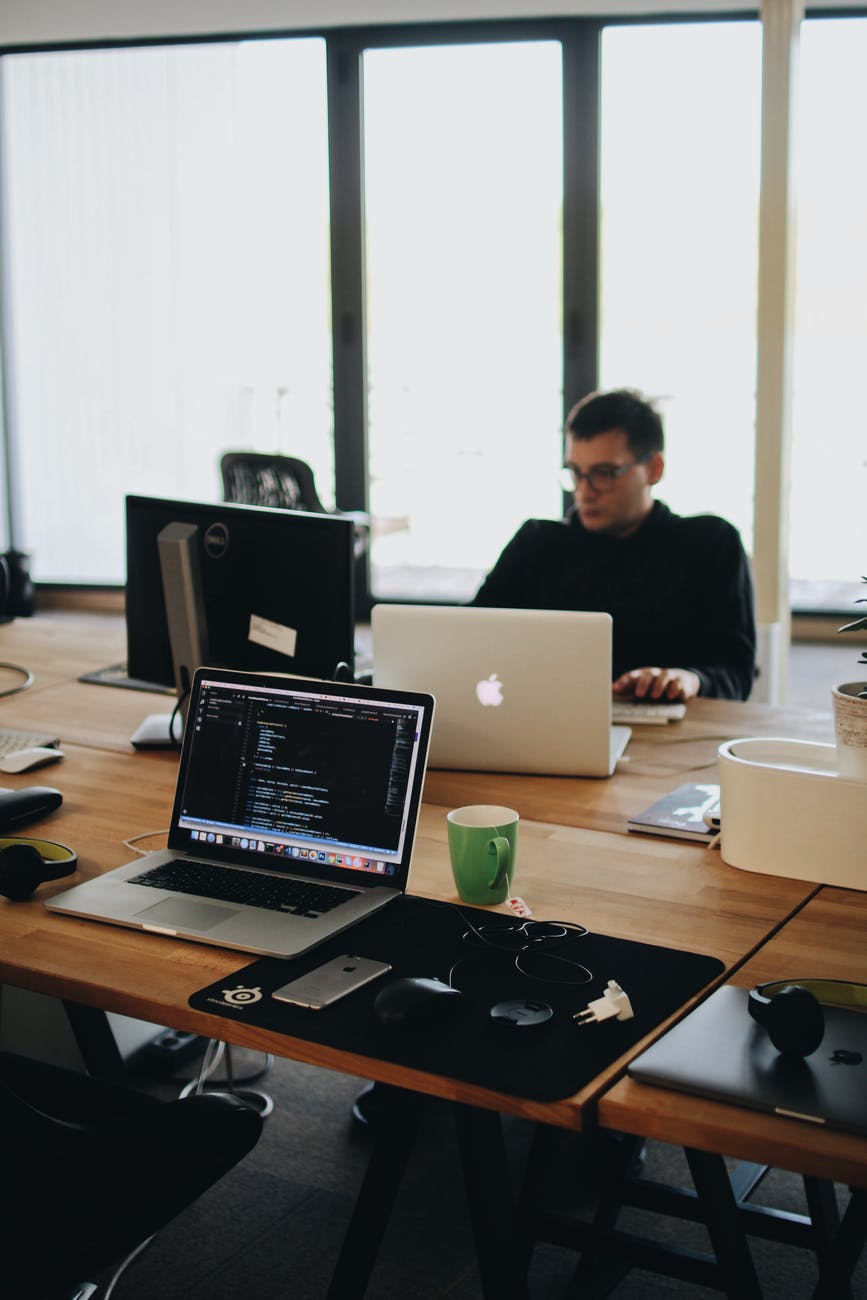 crunch time - man in black shirt sits behind desk with computers