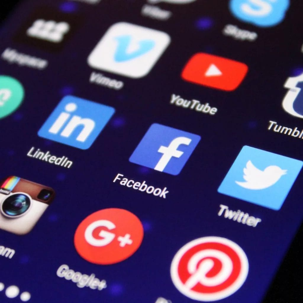 Social media icons are displayed on a cell phone for indie game marketing.