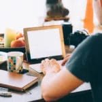A man sitting at a desk with a laptop and a cup of coffee, timing, marketing strategy.