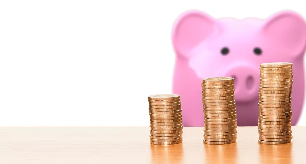 An indie piggy bank standing next to stacks of coins, offering smart finance tips and game budgeting advice.