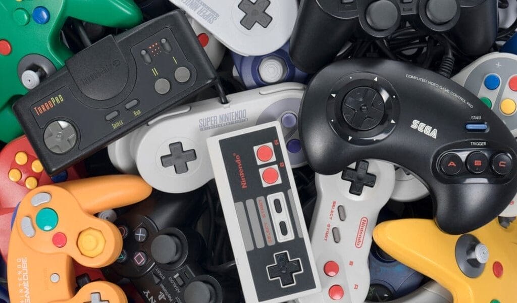 Retro Effect Tutorial with Unity Shader Graph A variety of video game controllers from different console generations, including Nintendo, Sega, and others, are clustered together in a pile with a subtle retro effect for added nostalgia.