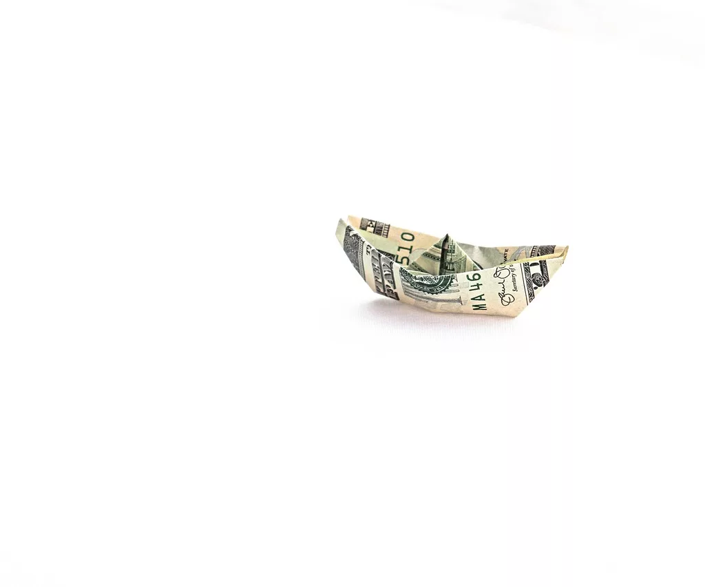 A dollar bill, symbolizing smart finance tips, sits on top of a white surface as part of an indie game budgeting strategy.