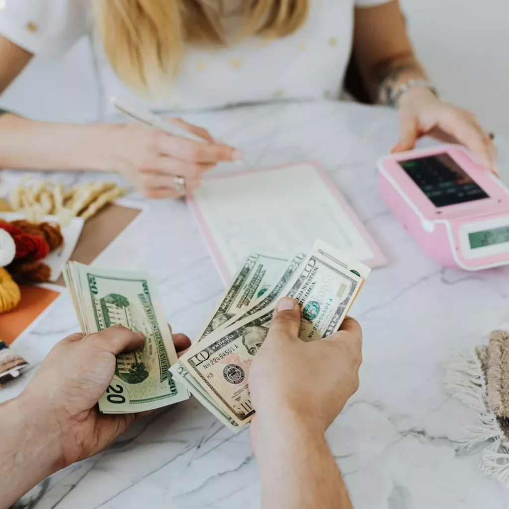 A woman and a man are discussing smart finance tips while holding money at a table.